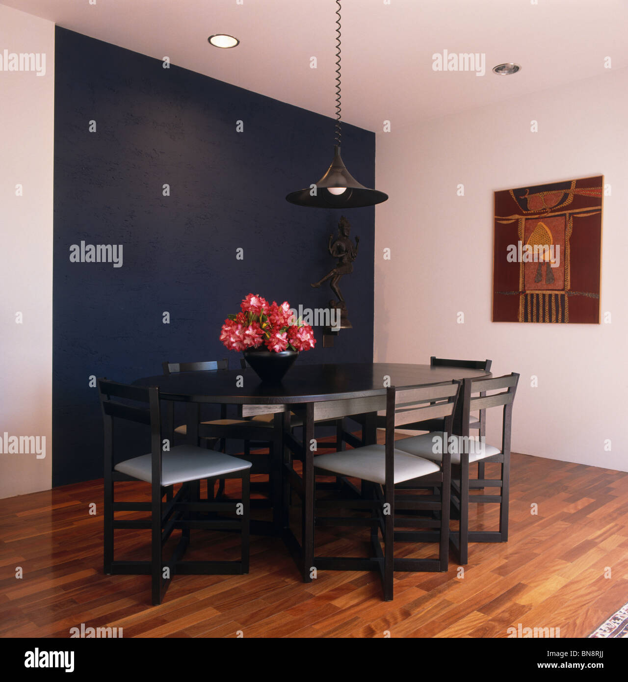 Blu scuro in parete bianca e moderna sala da pranzo con mobili di colore nero e il pavimento in legno Foto Stock