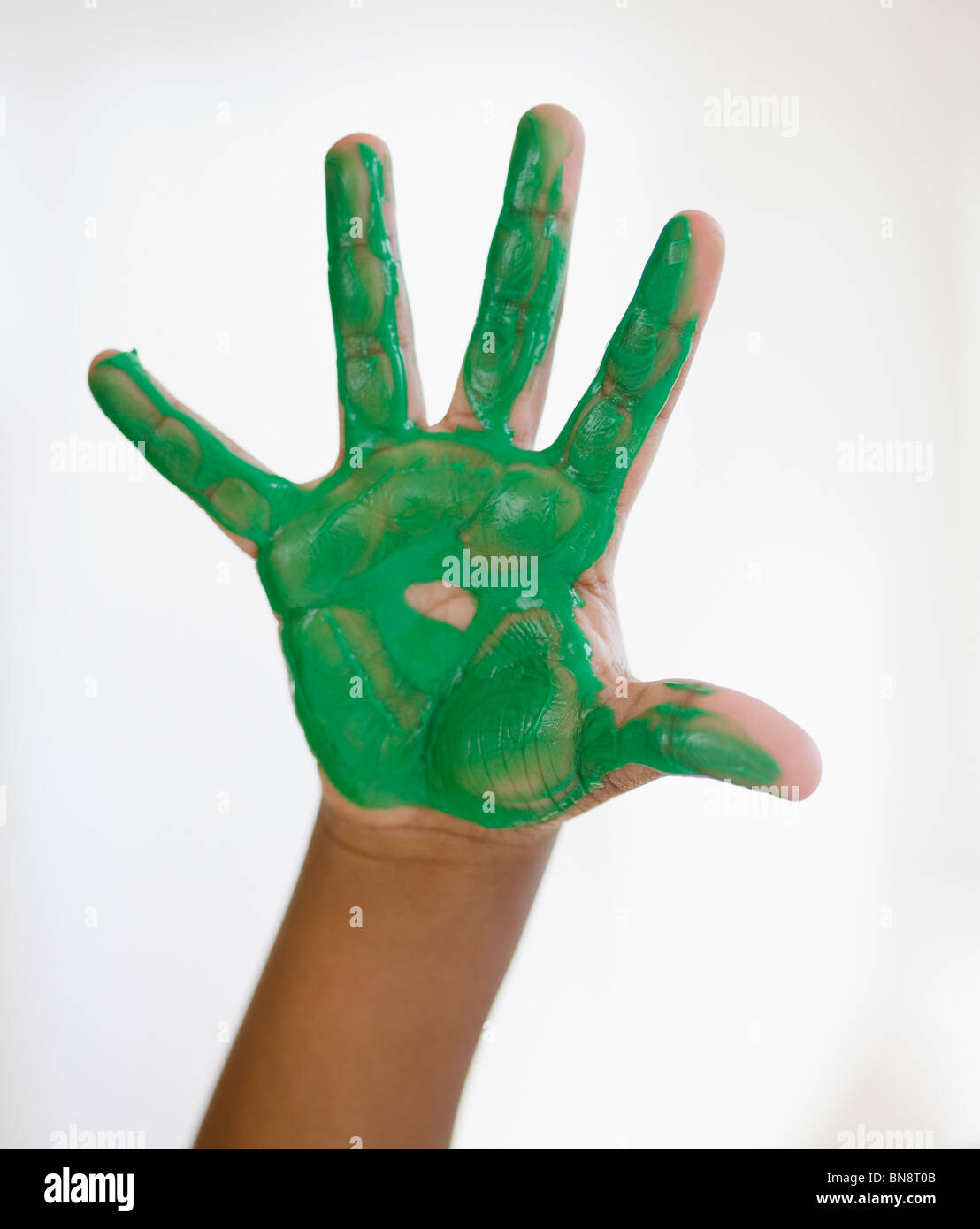 Black Boy con della vernice verde a portata di mano Foto Stock