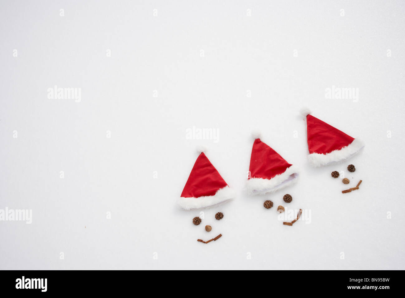 Volti nella neve indossando cappelli di Babbo Natale Foto Stock