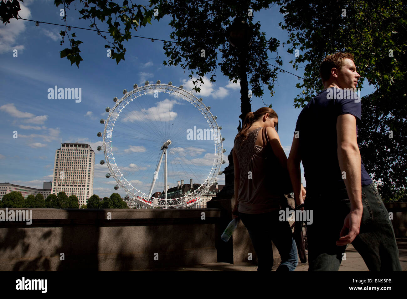 I turisti passano il London Eye. Uno di Londra più popolari attrazioni turistiche. Noto anche come il Millennium Wheel. Foto Stock
