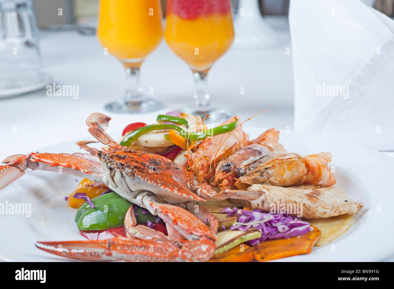 Piatti a base di frutti di mare freschi pasto di nuoto granchi e gamberi tigre con insalata su una piastra bianca con fresche bevande di frutta Foto Stock