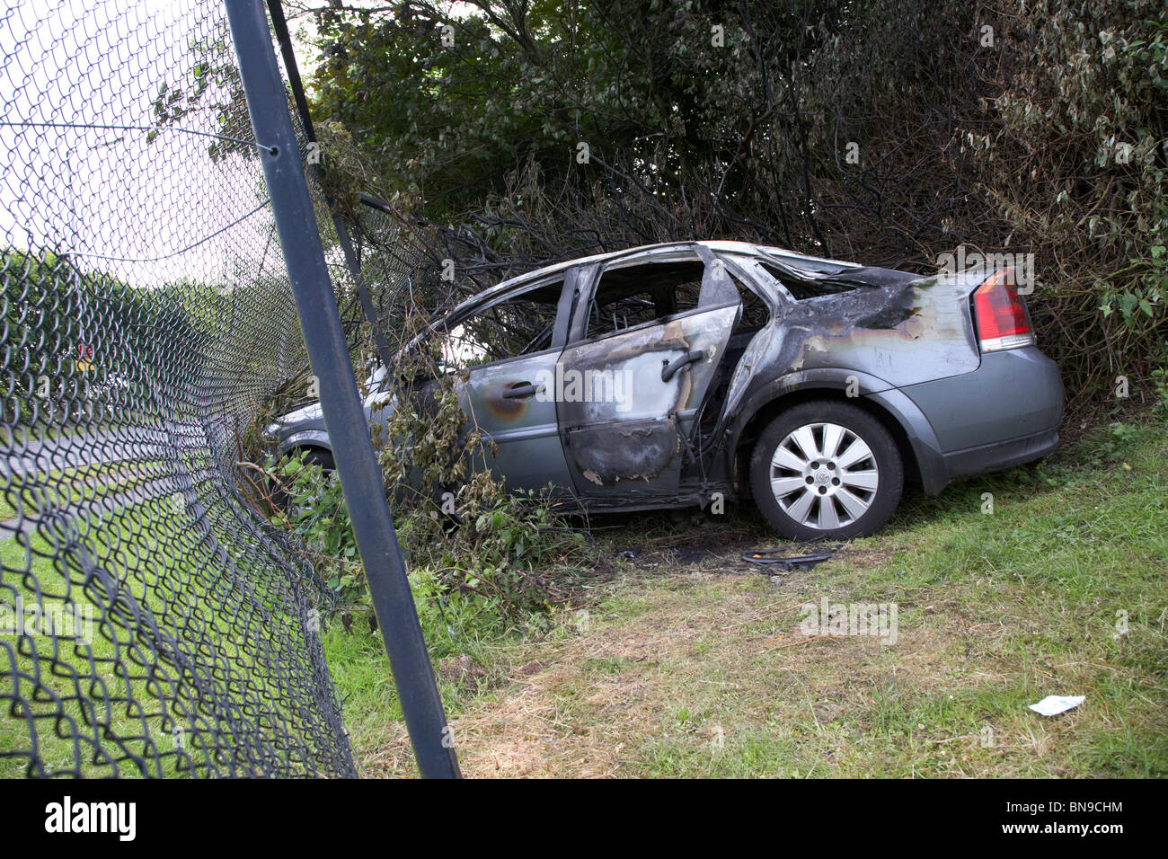 Bruciata furto di auto si è schiantato in una catena collegamento recinto nel Regno Unito Foto Stock