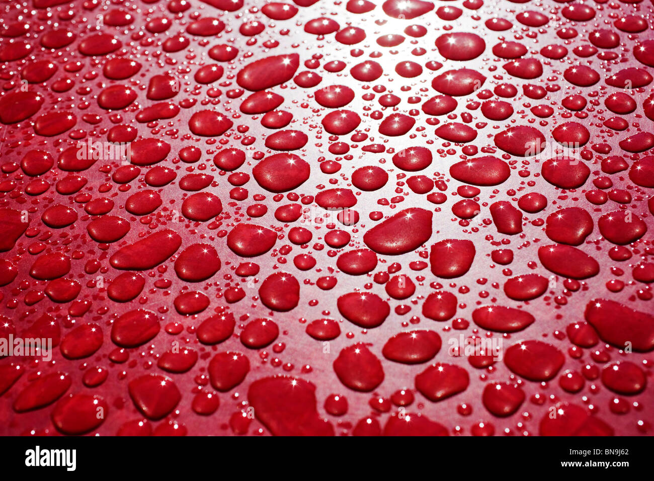Close up macro fotografia di gocce di pioggia su una tabella rossa Foto Stock