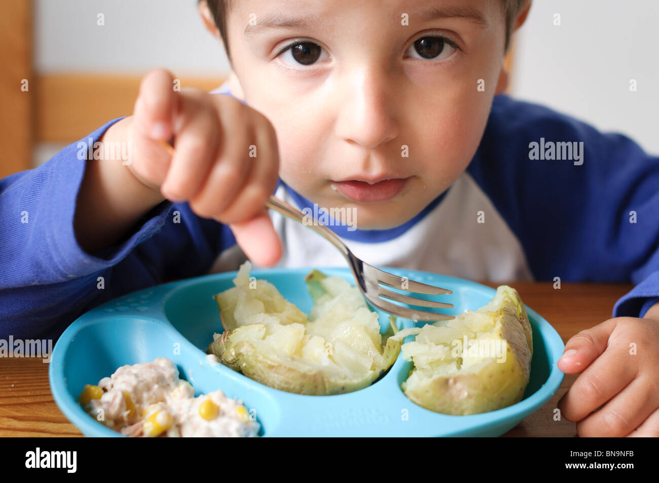 Bambino mangiare patate al forno Foto Stock