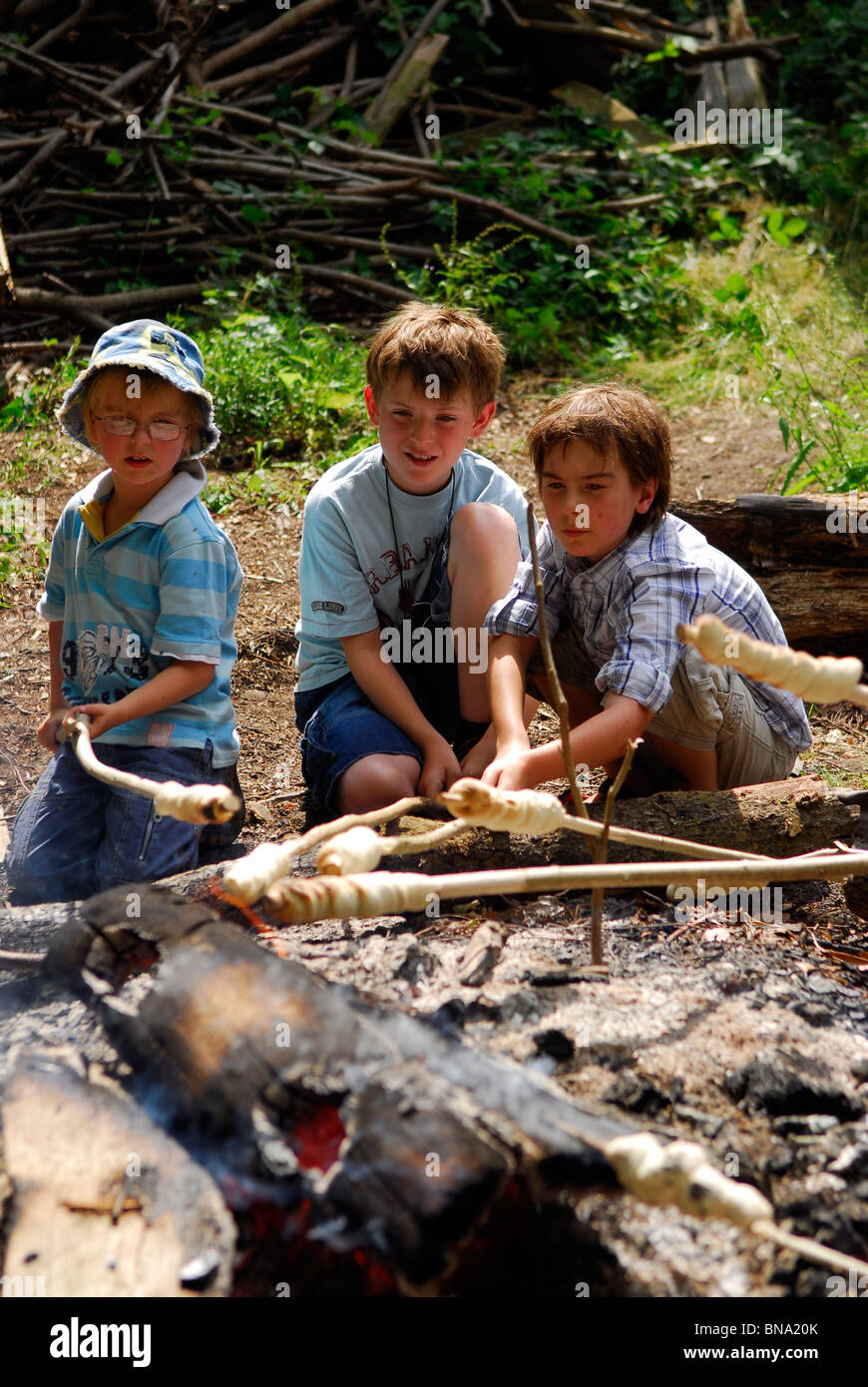 I giovani la cottura 'dampers' (pasta cotta sul fuoco aperto a fare il pane) in corrispondenza di una scout giorno di celebrazione, Haslemere, Surrey, Regno Unito. Foto Stock