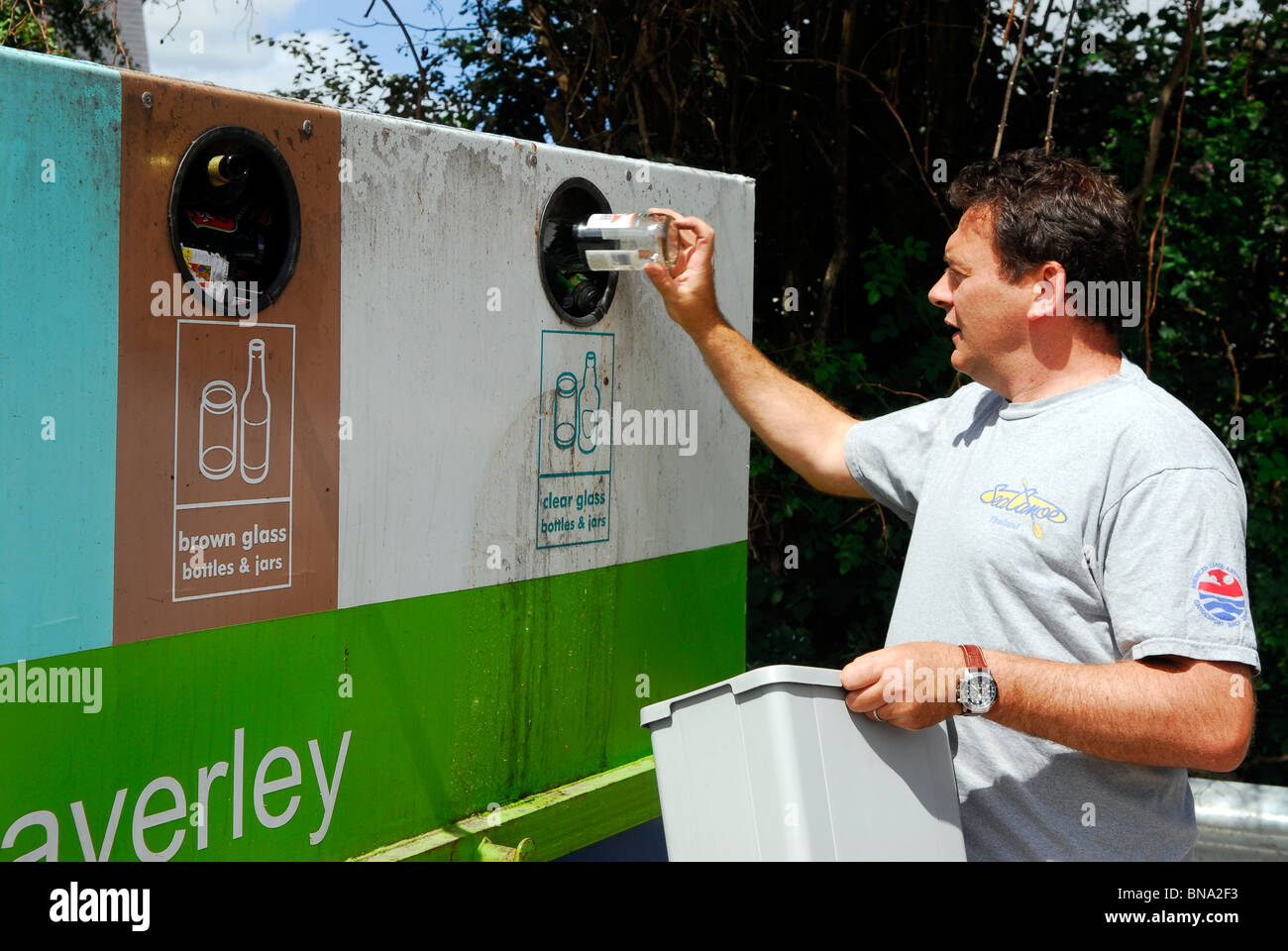 L'uomo ponendo in bottiglia bottle bank per il riciclaggio, Wey Hill, Haslemere, Surrey, Regno Unito. Foto Stock