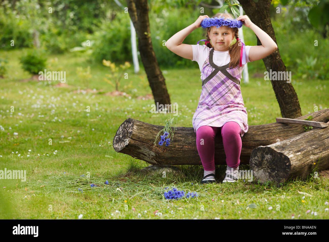 Bambina con una coroncina realizzata da fiori blu Foto Stock