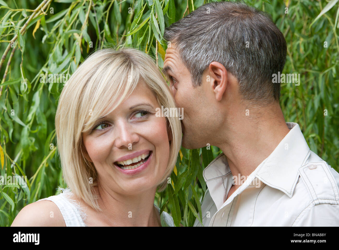L'uomo whispering nella donna di orecchio Foto Stock