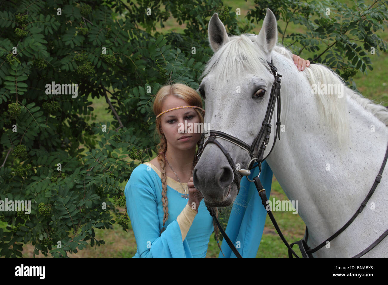 Ragazza slava in russo vestito con il suo cavallo bianco Foto Stock