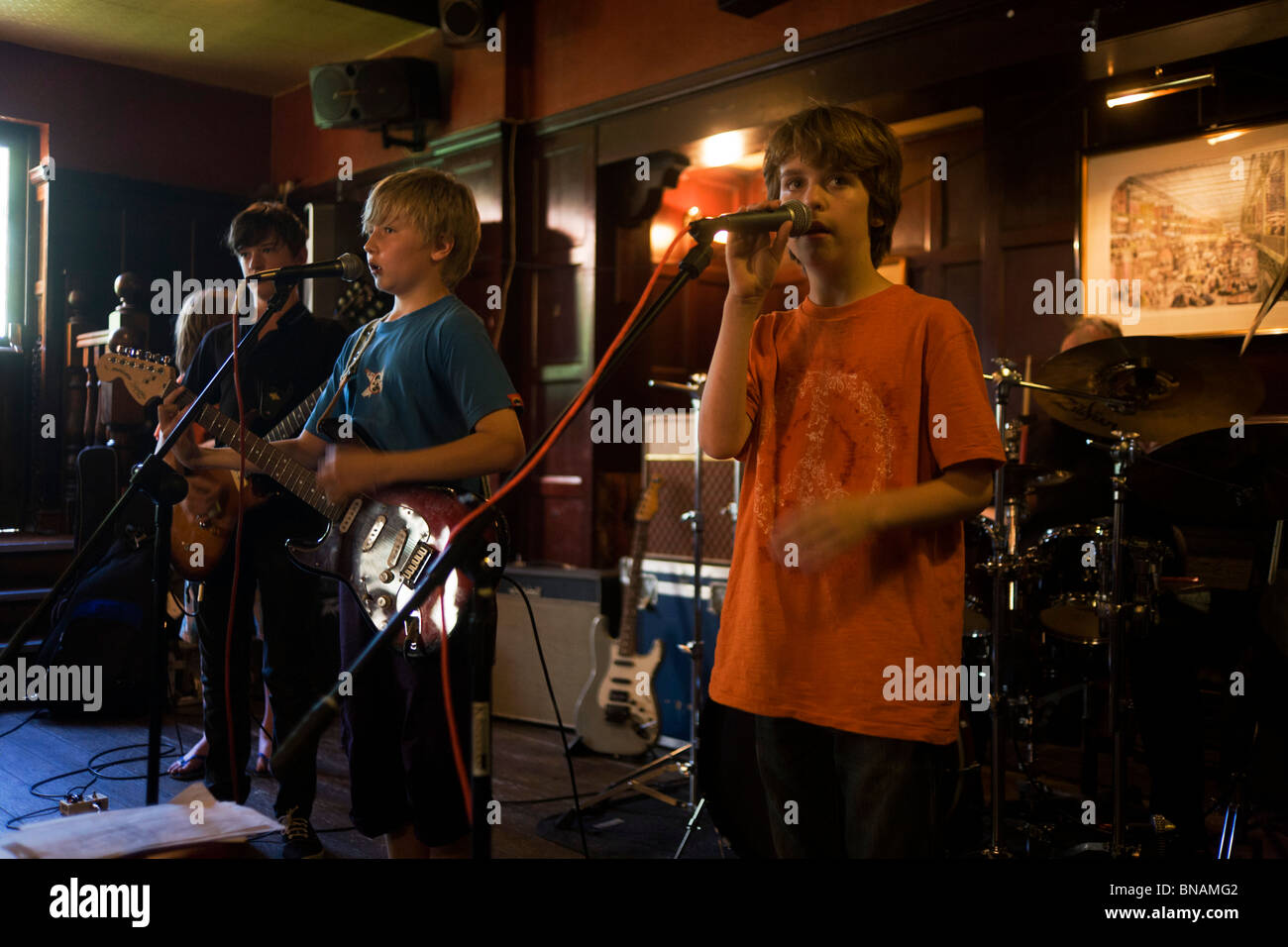 Scolari eseguire rock and roll song insieme come una band in un South London pub. Foto Stock