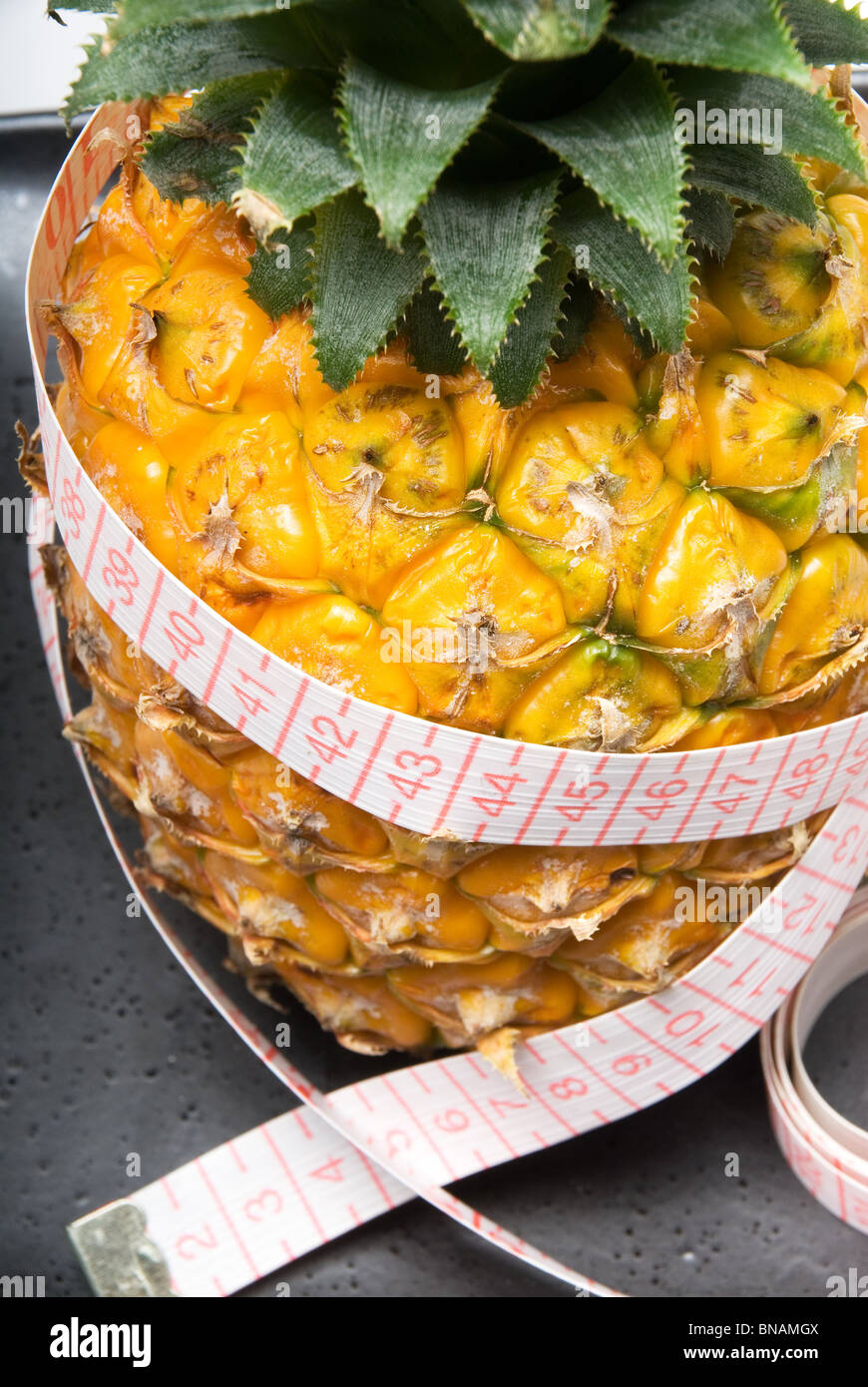 Mature vivid ananas su una piastra nera con metro a nastro Foto Stock