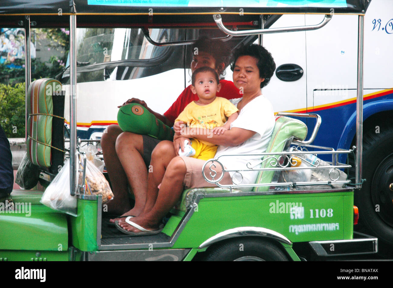 Una famiglia locale ride in una familiare verde-Tuk Tuk a Bangkok in Tailandia Foto Stock