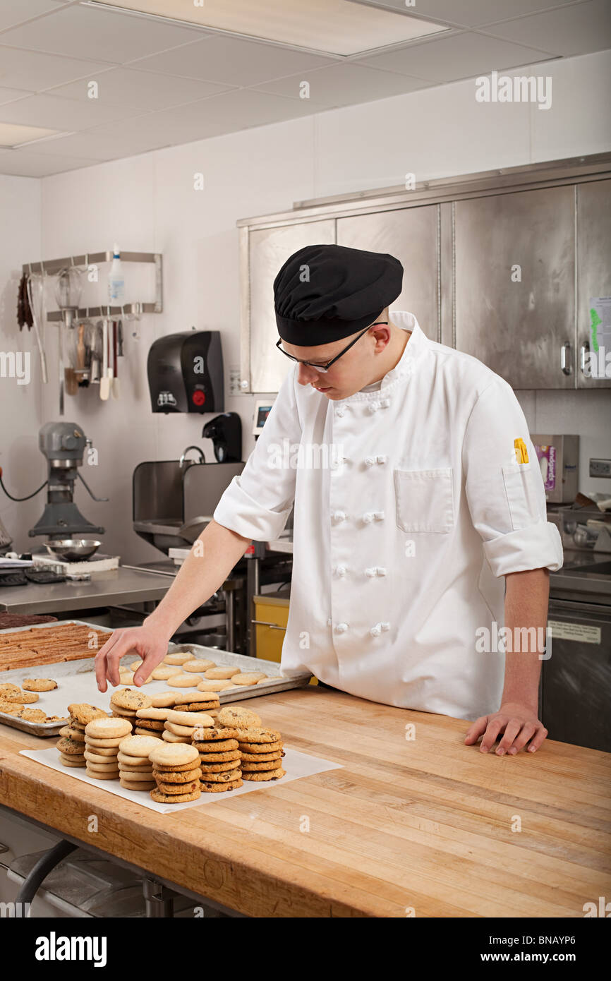 Lo chef maschio i biscotti di cottura in cucina commerciale Foto Stock