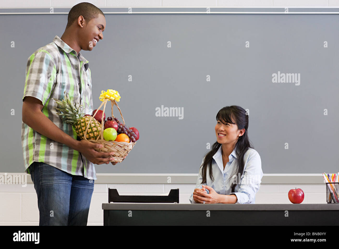 Maschio di alta scuola studente insegnante dando un cesto di frutta Foto Stock