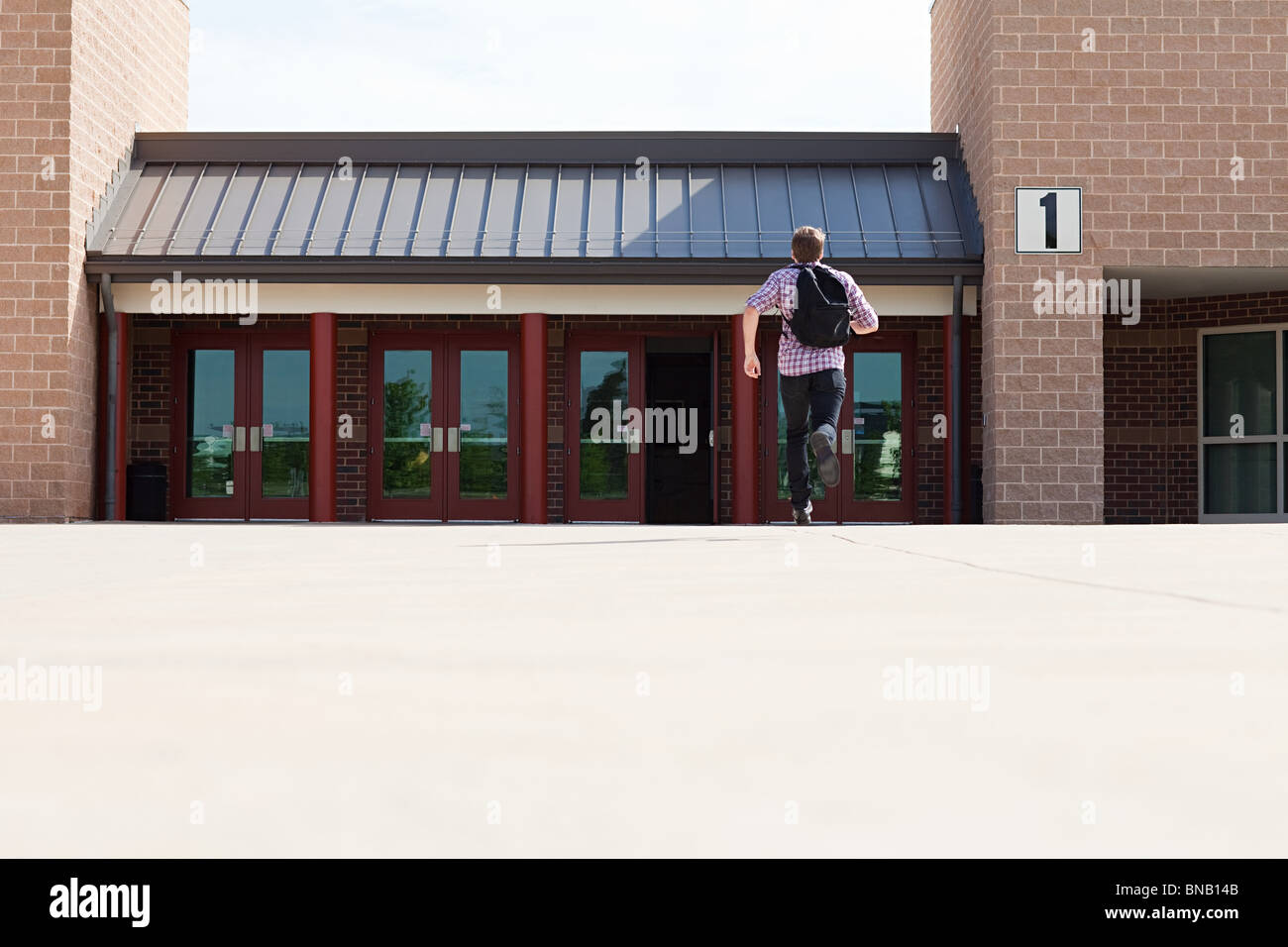 Maschio di studente di scuola superiore a correre verso la scuola Foto Stock