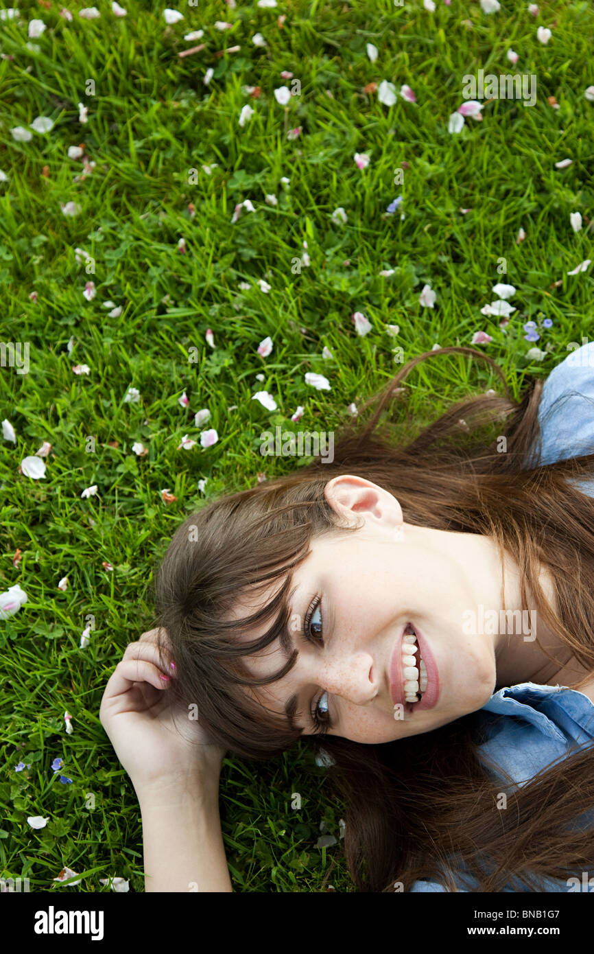 Giovane donna sdraiata sull'erba Foto Stock