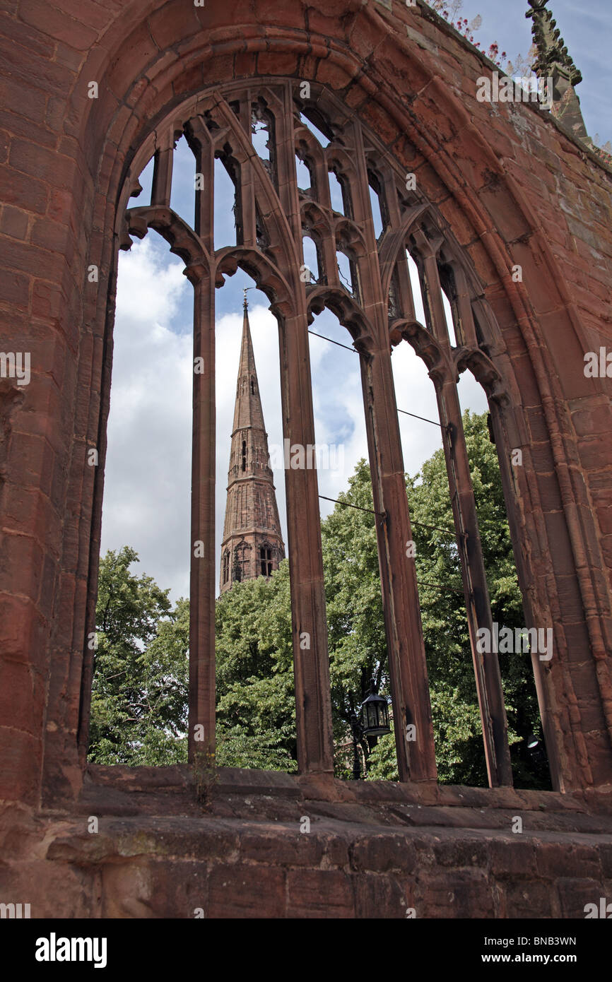 La guglia della chiesa della Santa Trinità visto attraverso le rovine della cattedrale di Coventry, Coventry City Centre, Inghilterra Foto Stock