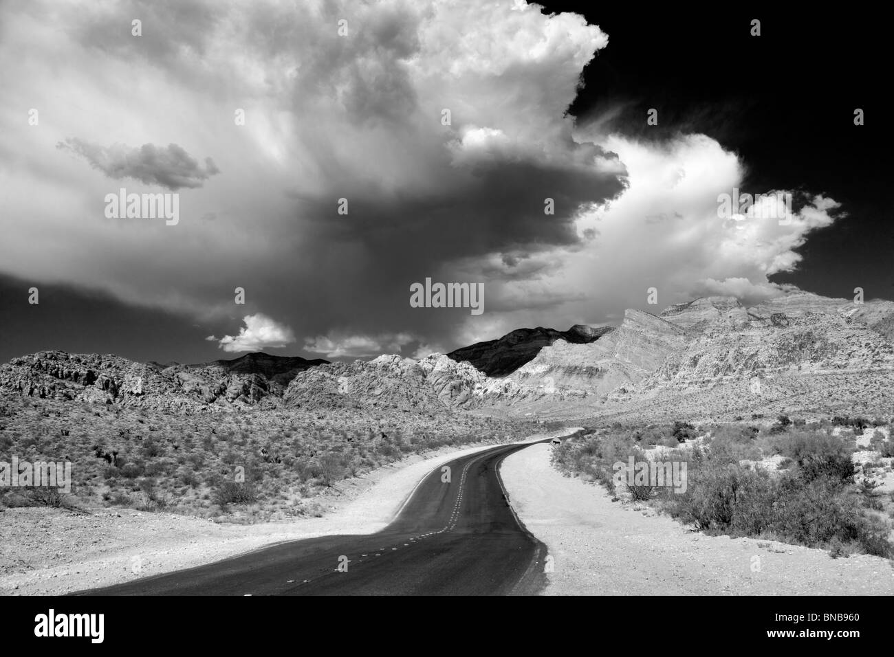 Strada e temporale di nuvole con formazioni rocciose nella Red Rock Canyon National Conservation Area, Nevada Foto Stock