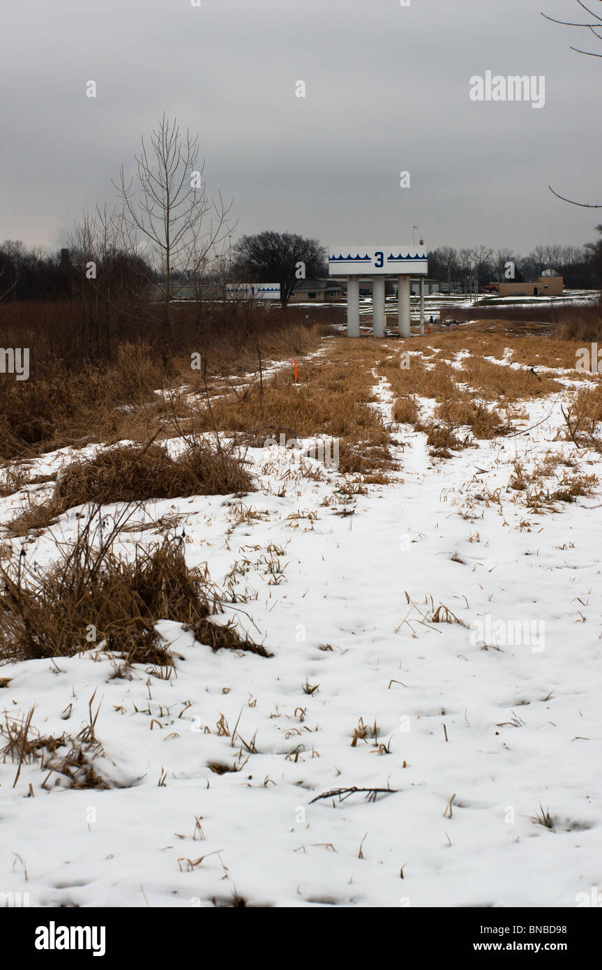 Guardando minaccioso nuvole di neve appendere dietro una città acqua bene alla fine di un campo della spazzola Foto Stock