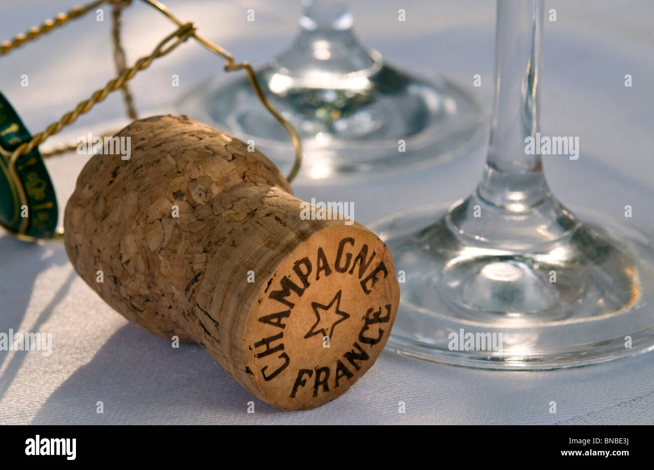 Champagne francese il sughero sulla tovaglia bianca con vetri a filo del telaio di fissaggio e il tappo Foto Stock