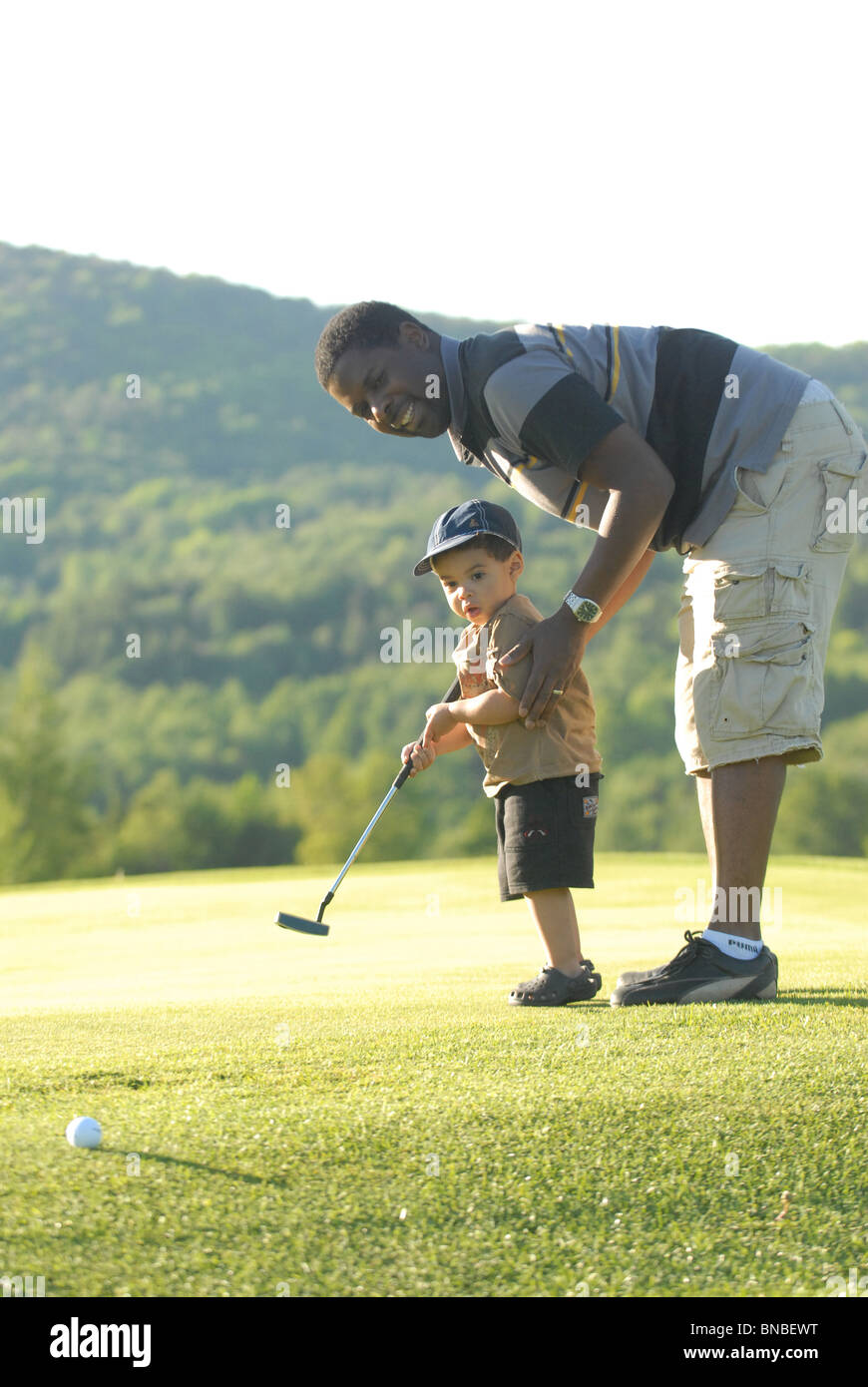 Un giovane nero golfista colpi di una sfera con suo padre a assistenza Sugarbush Resort Golf Club a Warren, Vermont. Foto Stock