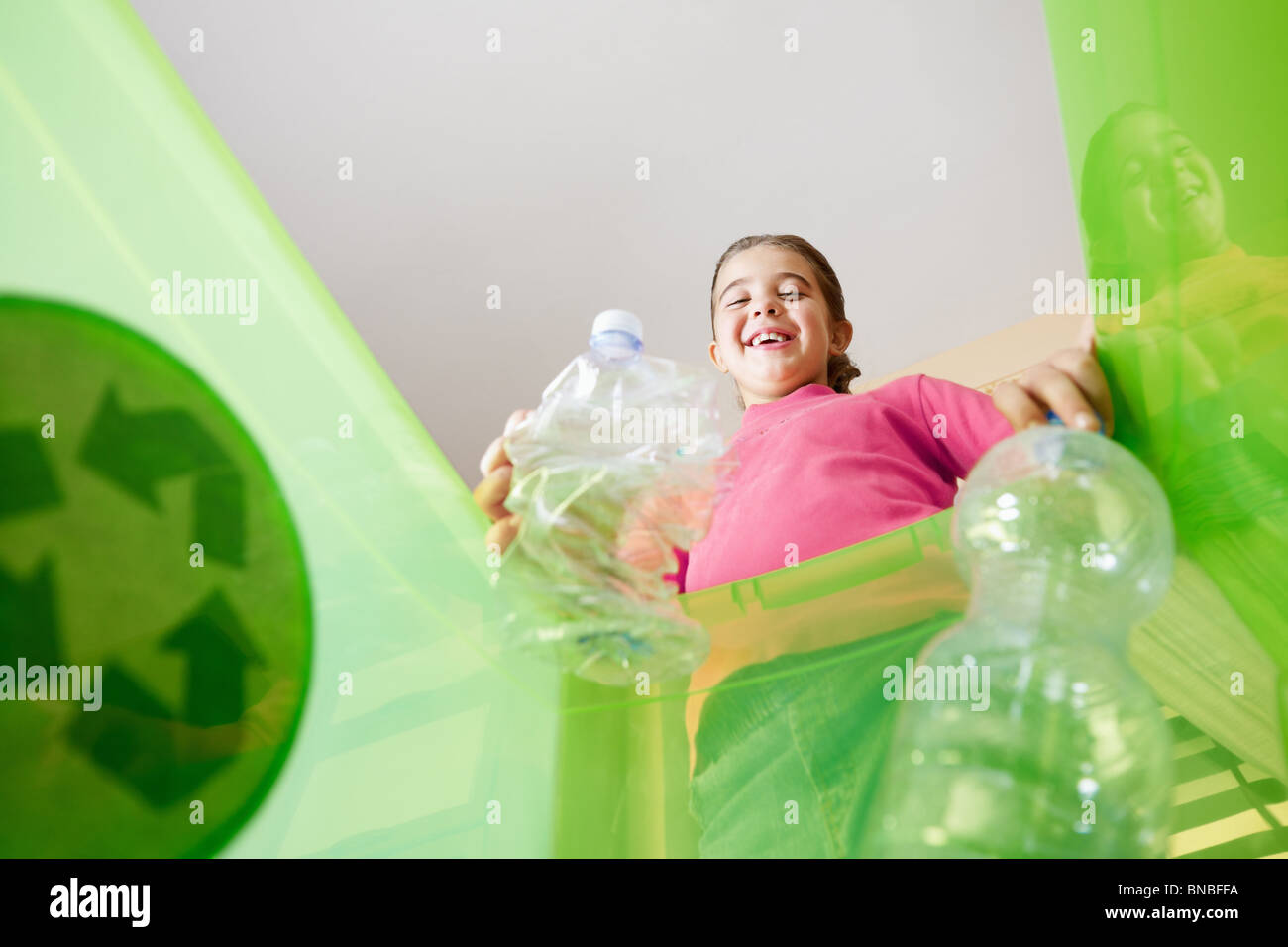 Ragazza con bottiglie di plastica per il riciclaggio, visto dal lato interno del contenitore di riciclaggio. Spazio di copia Foto Stock