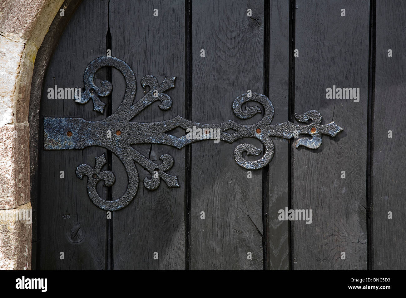Vecchia porta di legno scuro con elaborati cerniera di ferro Foto Stock