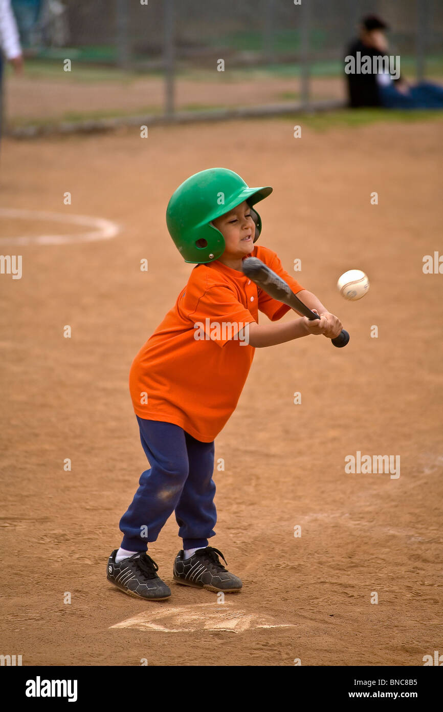 5 anno di età del bambino ispanica bambini sport ragazzo swinging bat batting sfera durante t palla di gioco. Stati Uniti © signor © Myrleen Pearson Foto Stock