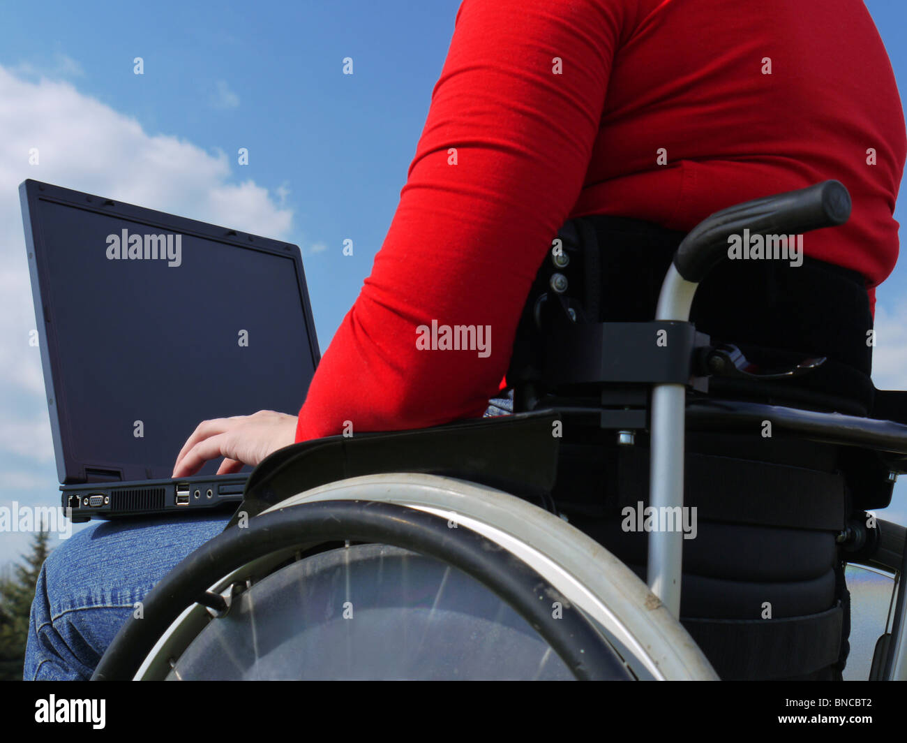 Donna disabile su sedia utilizzando laptop all'aperto Foto Stock