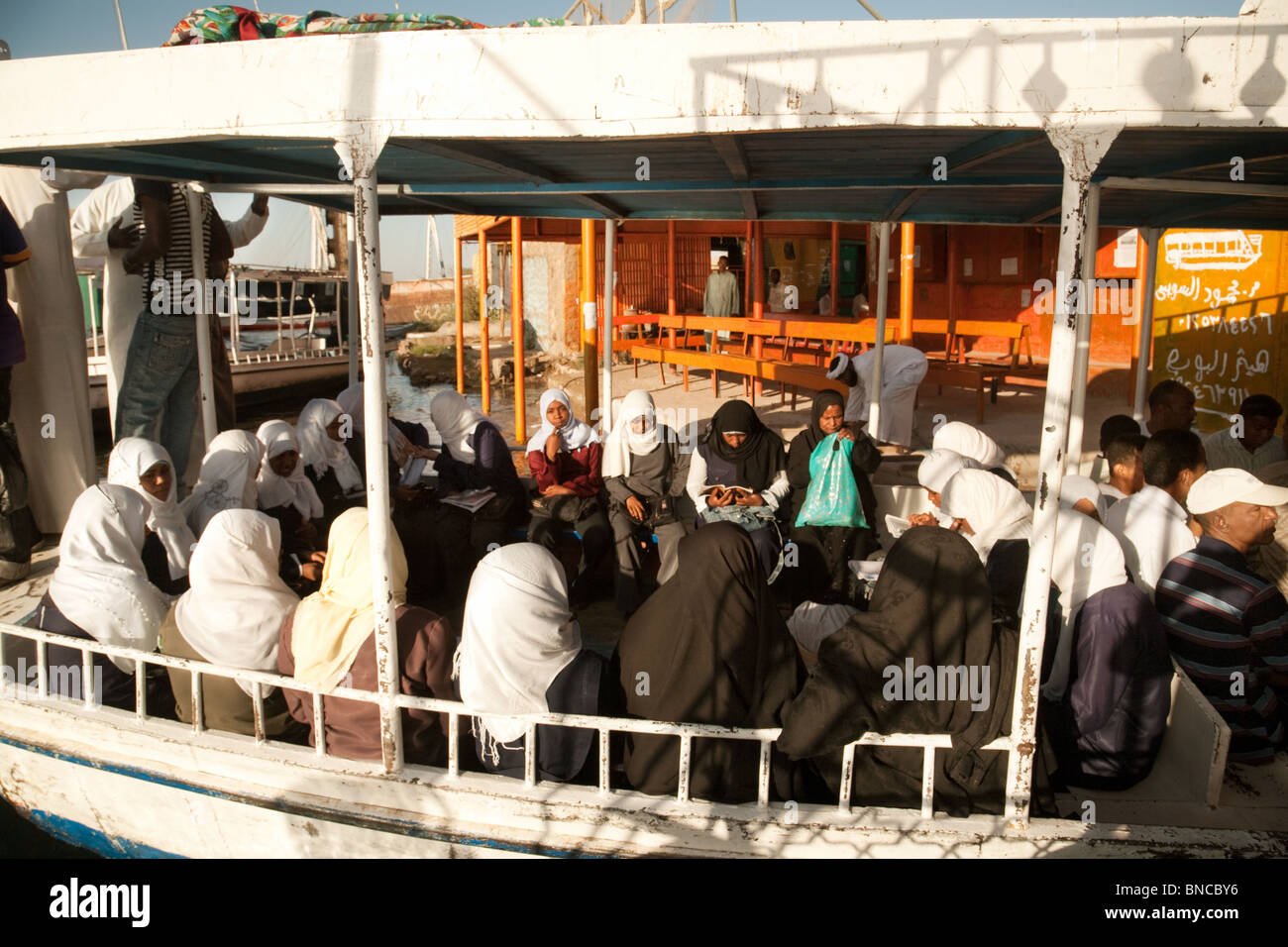Stile di vita in Egitto; donne egiziane nubiane locali a bordo di un traghetto per portarle attraverso il fiume Nilo per lavorare ad Assuan, Alto Egitto Africa Foto Stock
