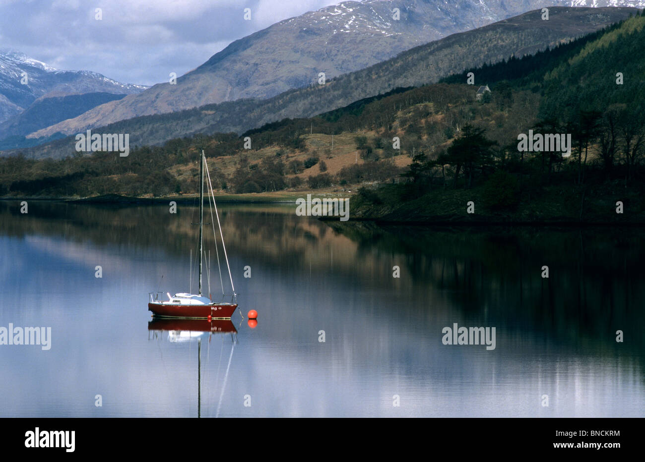Un rosso barca a vela ancorata in un scozzese Loch a Skye Foto Stock