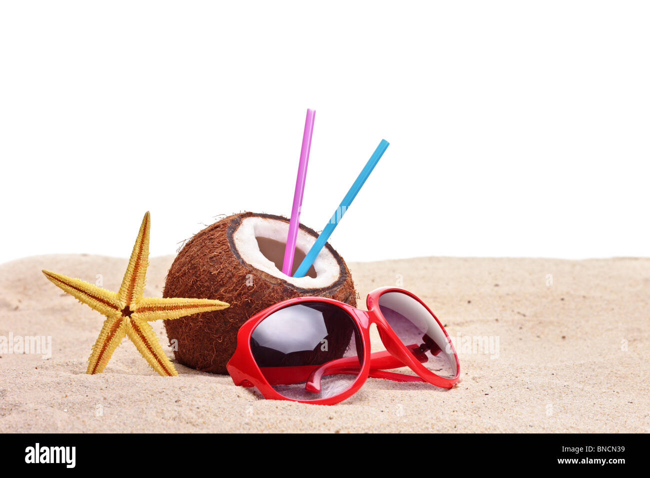 Una noce di cocco, stelle marine e un paio di occhiali da sole su di una spiaggia Foto Stock