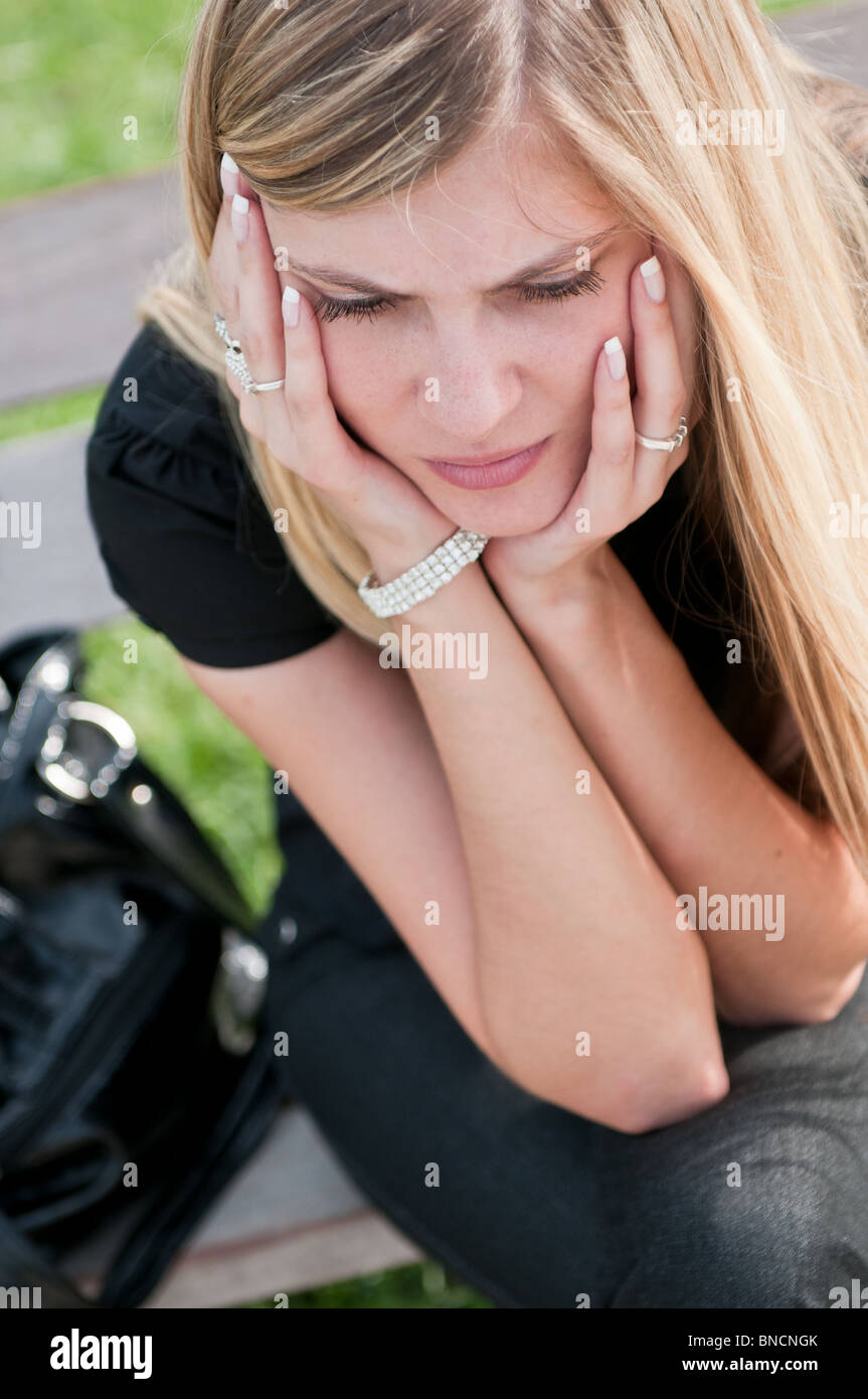 Giovani preoccupati bella donna posa sul banco di lavoro - testa in mani Foto Stock