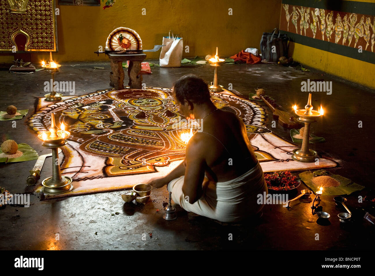Un bramino Namboodiri sacerdote si prepara per una puja (rituale preghiera) da un Kalam piano immagine della dea Indù Kali a un tempio. Foto Stock