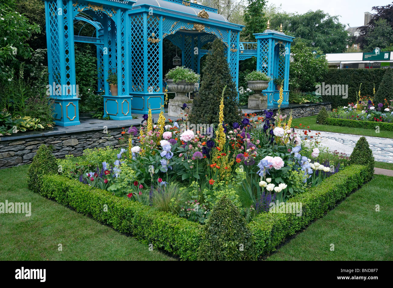 Uccelliera vittoriana giardino con fiori colorati in confini Foto Stock