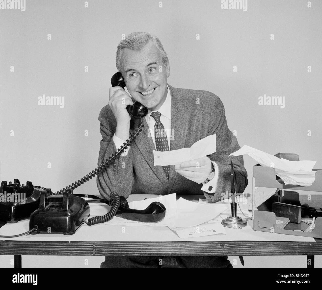 Imprenditore tenendo un controllo e parlando al telefono Foto Stock