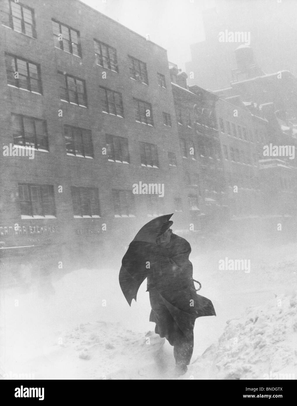 Uomo con ombrello a piedi durante una bufera di neve Foto Stock