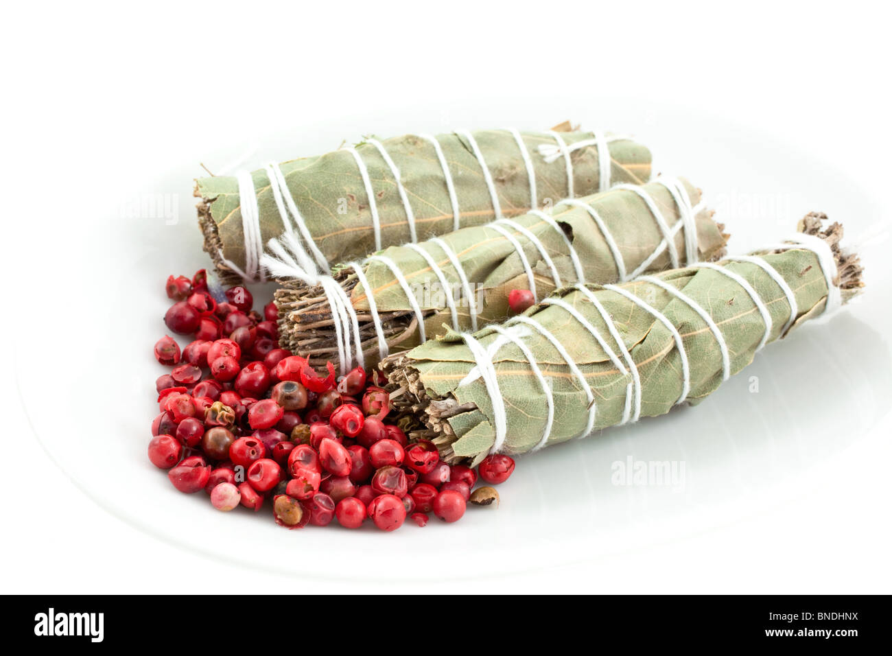 Tre mazzi di fiori secchi garni e pepe rosa su sfondo bianco Foto Stock