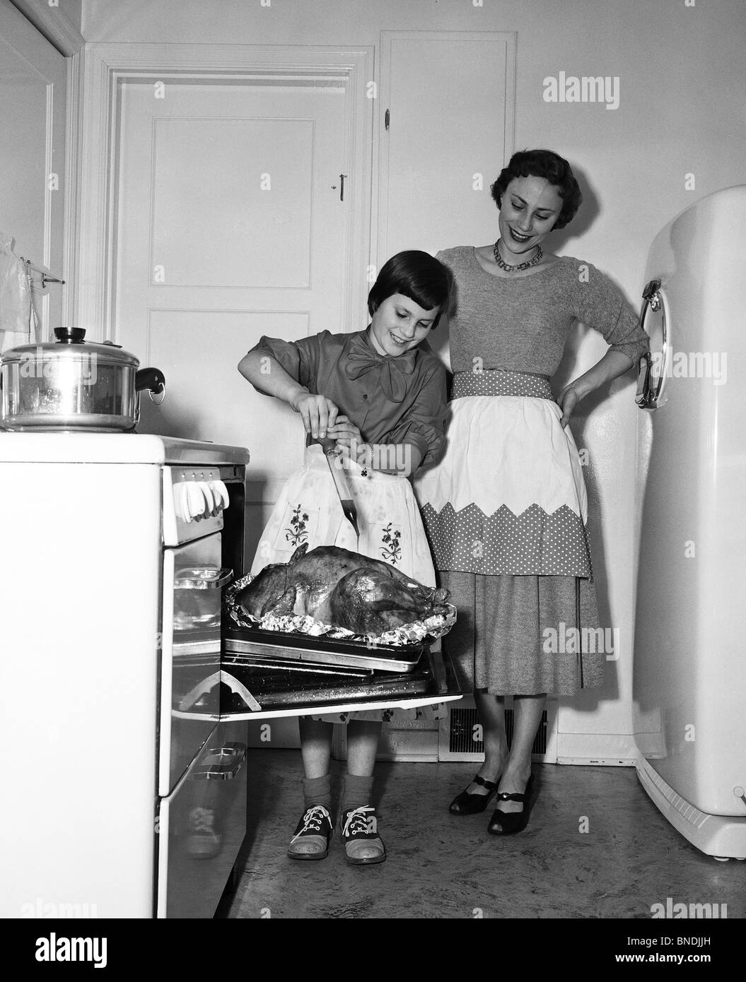 Madre guardando a sua figlia di irrorare una Turchia Foto Stock