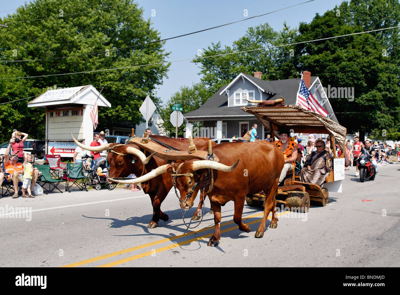 Uomo vestito come Fred Flintstone dei buoi di guida nella più antica indipendenza continua parata del giorno in America in Pekin, Indiana Foto Stock