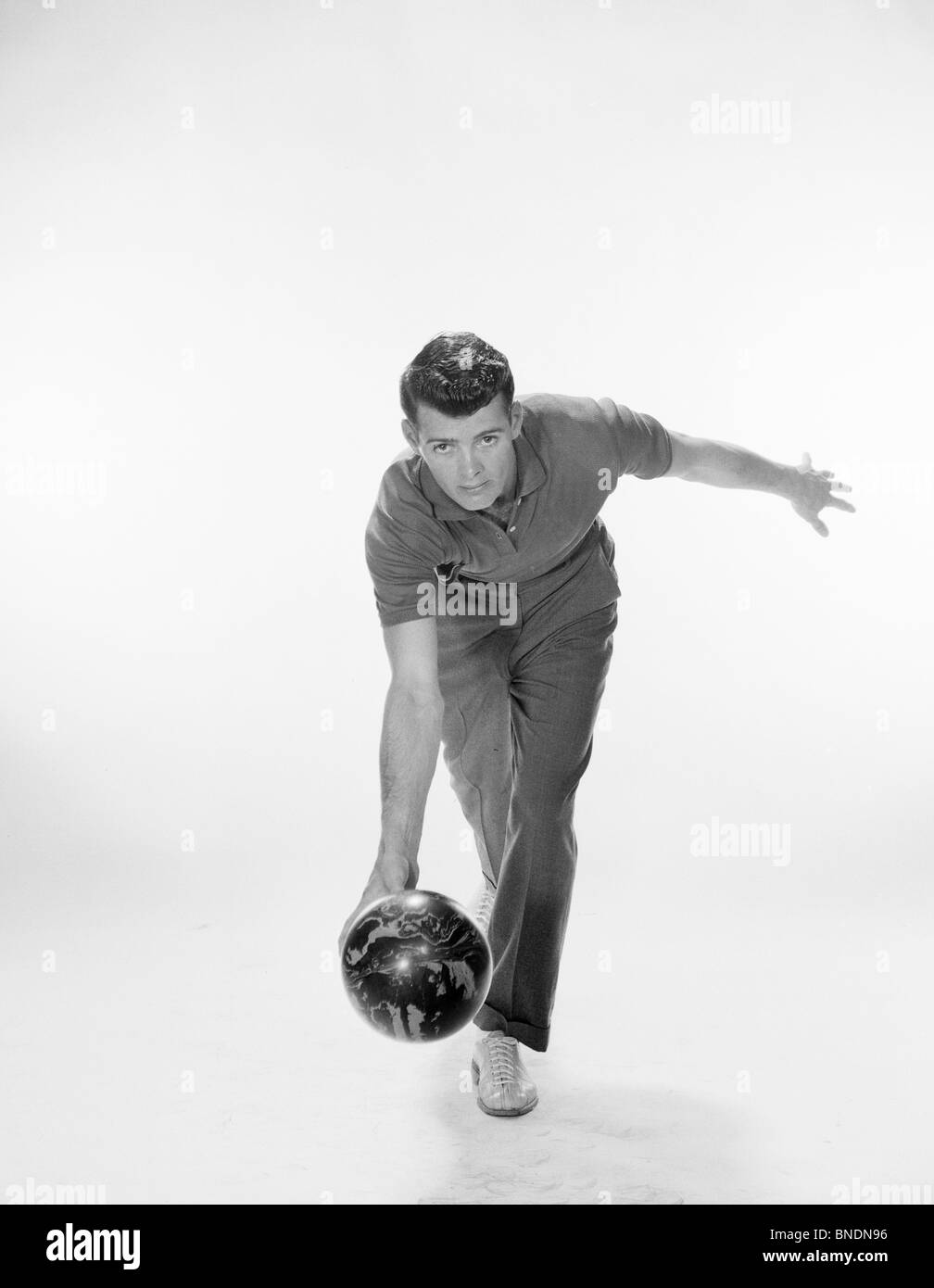 Giovane uomo facendo rotolare una palla da bowling Foto Stock