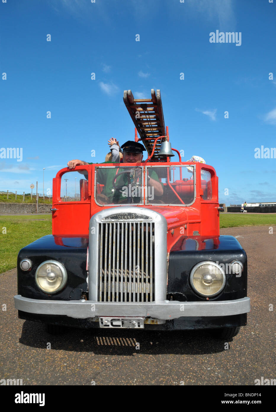Una miniatura 1950 motore fire. Un autista si prepara a prendere un paio di bambini per un giro in esso. Foto Stock