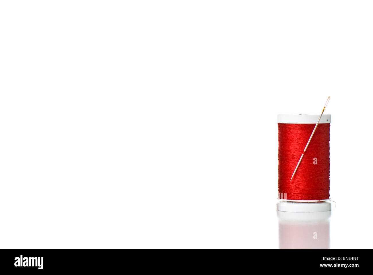 Un rocchetto di filo rosso e ago Foto Stock