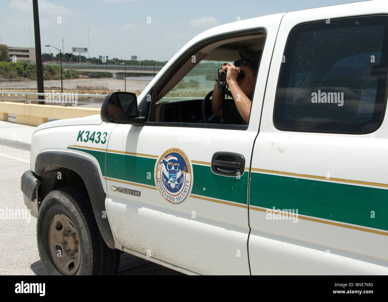 Stati Uniti Pattuglia di Confine agente utilizza un binocolo per cercare attività illegale lungo gli Stati Uniti-Messico confine vicino Laredo, Texas, Stati Uniti d'America Foto Stock