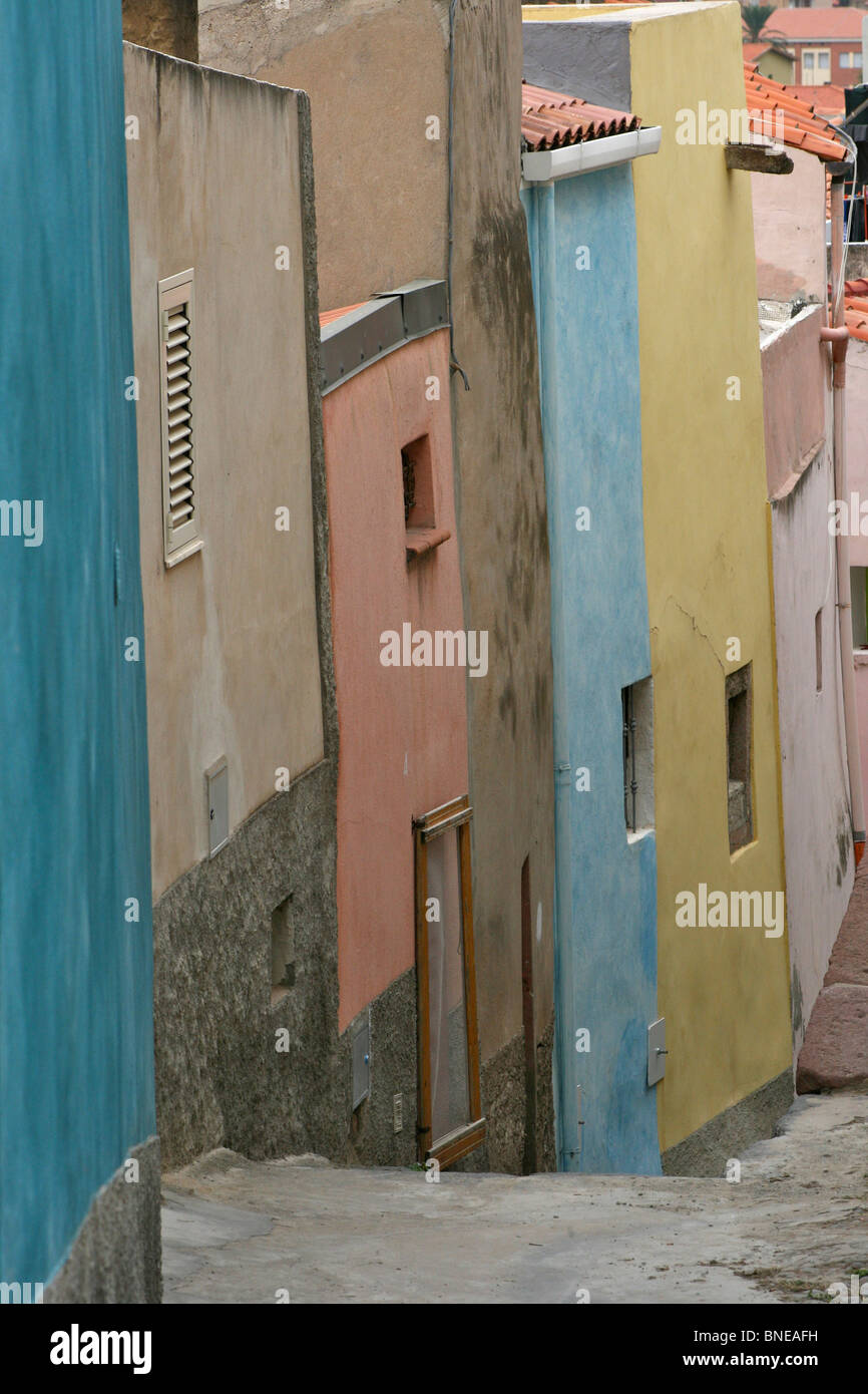 Intonaco colorato di fronte case a schiera la linea una stretta e ripida strada di Bosa, Sardegna Foto Stock