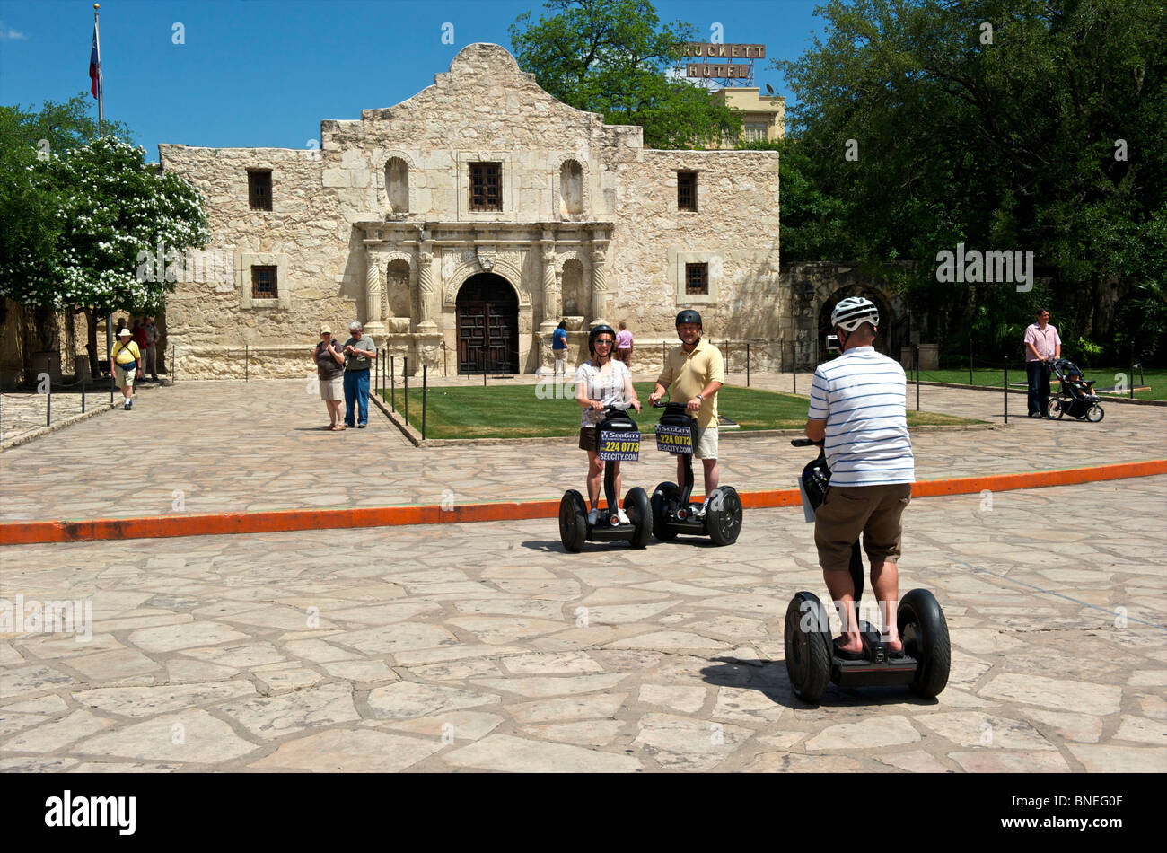 I turisti e i turisti su segways che posano per una fotografia al storico Alamo mission, simbolo di indipendenza del Texas in Texas, Stati Uniti d'America Foto Stock