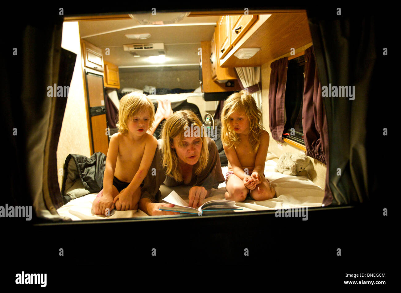 Madre la lettura di una storia prima di addormentarsi per i suoi figli in un camper RV in Texas, Stati Uniti d'America Foto Stock