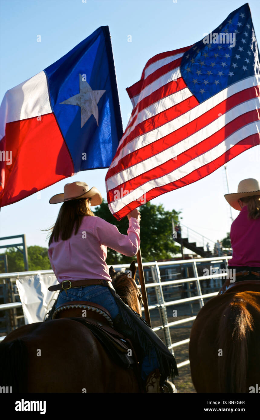 Cowgirls sventola bandiera nel piazzale di stoccaggio sulla cerimonia di apertura di PRCA Rodeo evento in Texas, Stati Uniti d'America Foto Stock