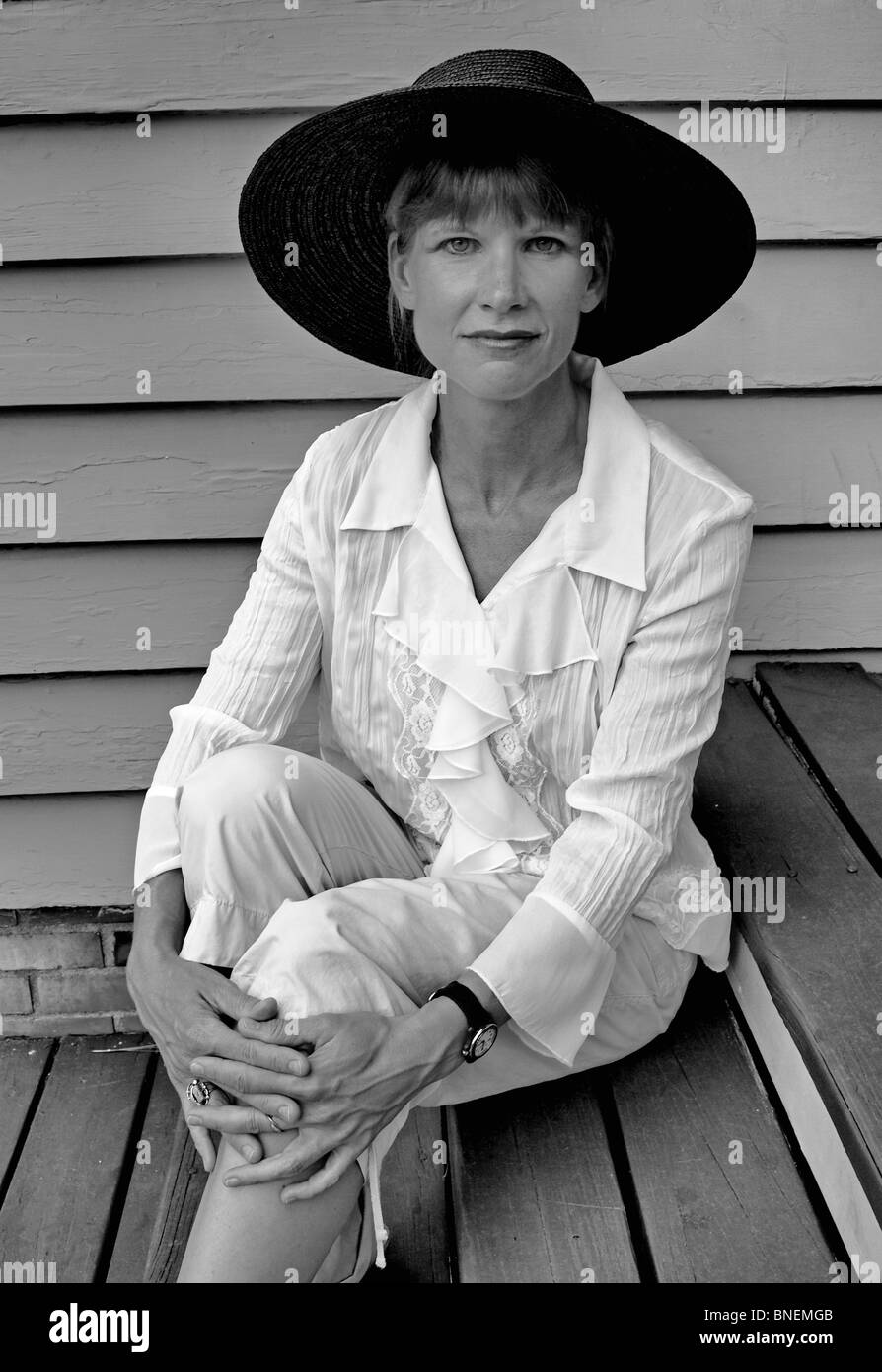 Modello di donna femmina in ampia bordata cappello nero con camicetta bianca guardando direttamente nella fotocamera mani moda Foto Stock