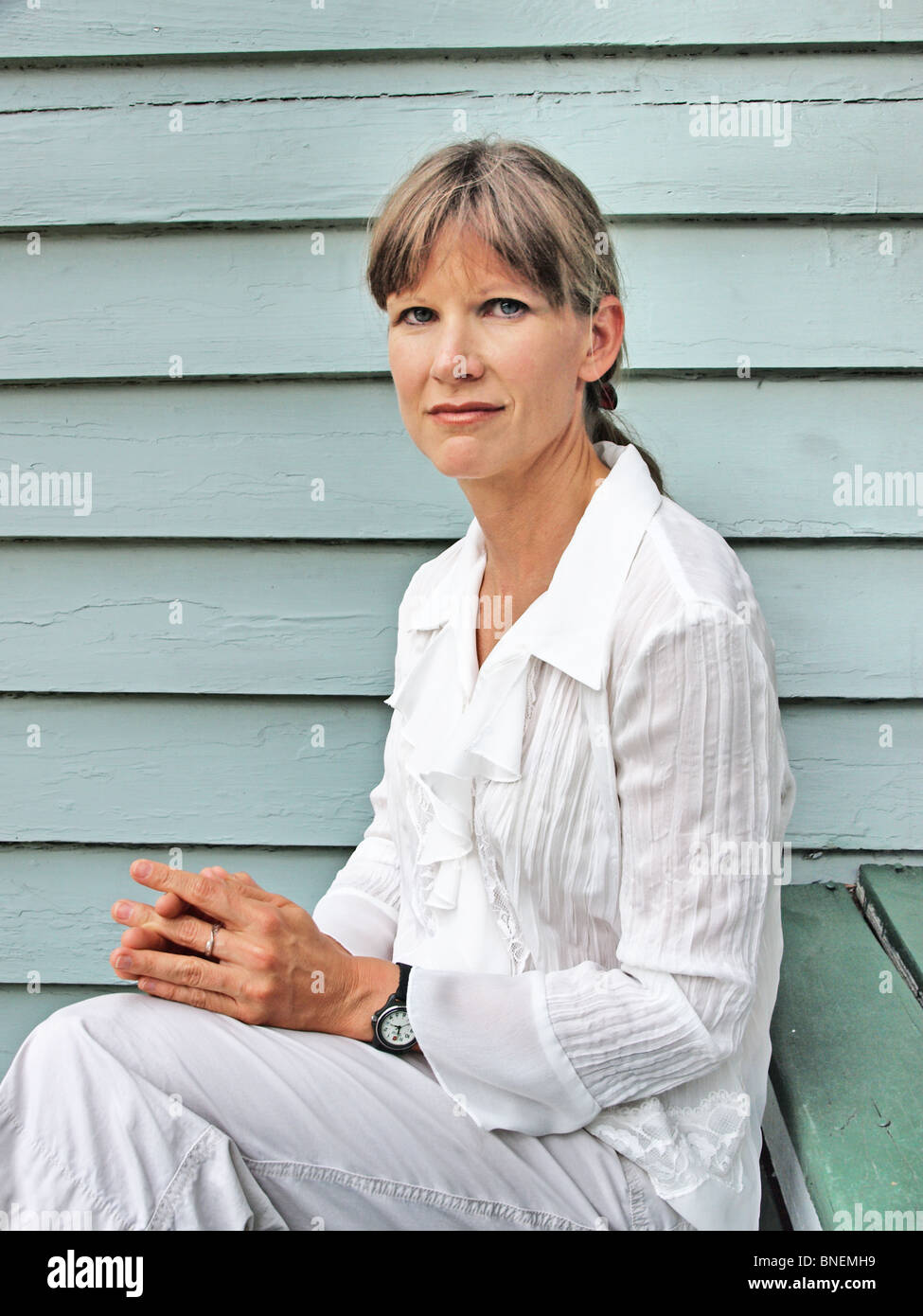 Modello di donna femmina in bianco frilly blusa con capelli tirati indietro guardando direttamente nel ritratto della fotocamera Foto Stock